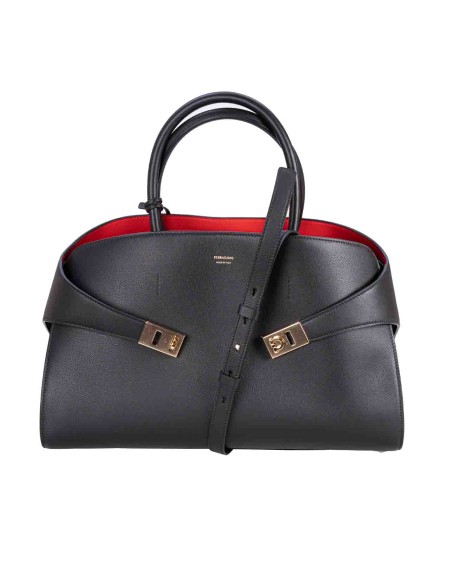 Shop SALVATORE FERRAGAMO  Bag: Salvatore Ferragamo Hug handbag.
Large and roomy, it features a special construction with an asymmetrical back that embraces the side gussets and fastens with golden-finish Gancini buckles.
Closed internally with a ring, it is completed with a key ring charm and a lined zip pocket.
The rectangular feet with signature ensure protection on the bottom.
Dimensions: height 24.0 CM length 38.0 CM depth 22.0 CM.
Composition: 100% calf leather.
Made in Italy.. 215921 767651-012